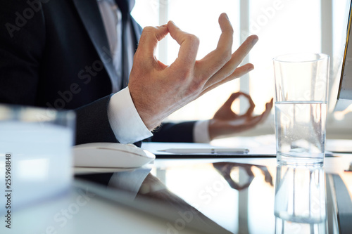 Hands of young contemporary office worker over desk during meditation and relaxation at break