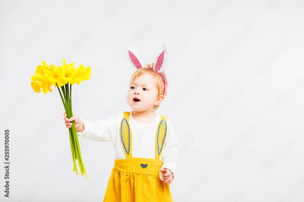 Smiling cute baby child in rabbit costumewith a bouquet of yellow daffodils on a white background. Smiling cute baby child in rabbit costumewith a bouquet of yellow daffodils on a white background.