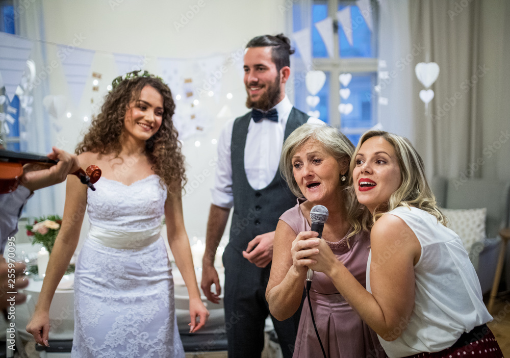 A young bride and groom with other guests dancing and singing on a wedding reception. A young bride and groom with other guests dancing and singing on a wedding reception.