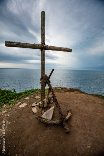 Cross and anchor on the mountain on the background of sea and sky