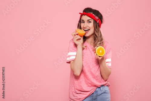 Portrait of a girl with oranges in hand, on a pink background