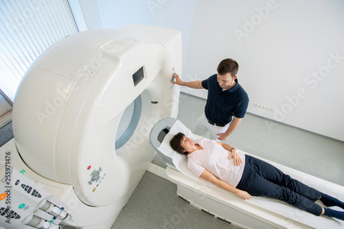 Computertomographie in der Radiologie, Patientin auf Untersuchungstisch, MTRA erklärt die Untersuchung, Top View photo