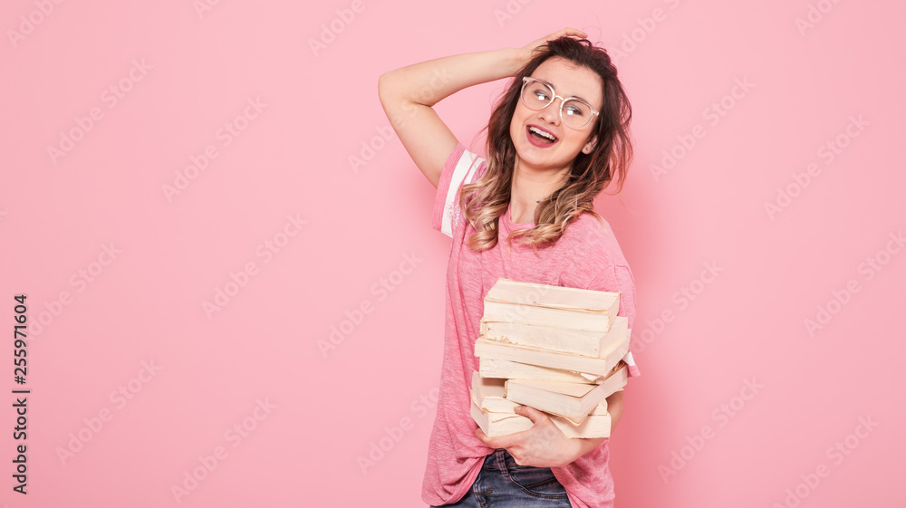 Portrait of a girl with a stack of books on a pink background Portrait of a girl with a stack of books on a pink background