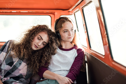 Young female friends on a roadtrip through countryside, sitting in minivan.