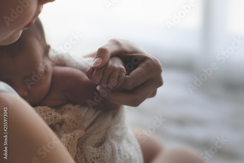 Close up Mother holding hands Asian female newborn baby  and sunlight in the morning. Cute little girl  three weeks old. Health, care, love, relationship concept. photo