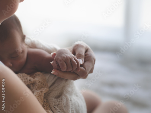 Close up Mother holding hands Asian female newborn baby  and sunlight in the morning. Cute little girl  three weeks old. Health, care, love, relationship concept.