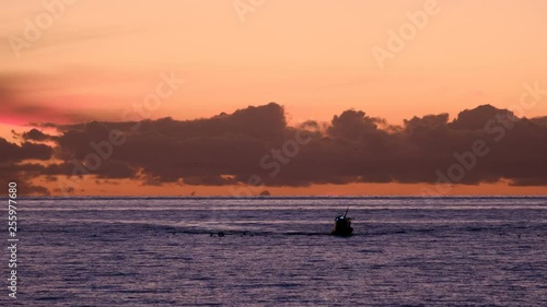 Long shot of fishing boat returning from work.