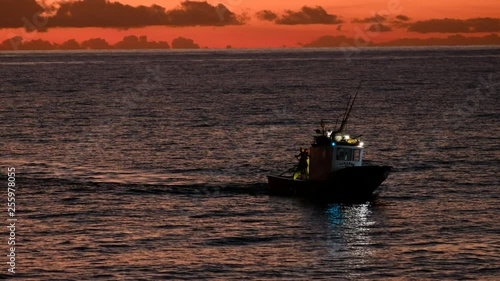 Medium shot of fifhing boat returning at dusk