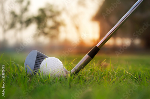 Golf clubs and golf balls on a green lawn in a beautiful golf course