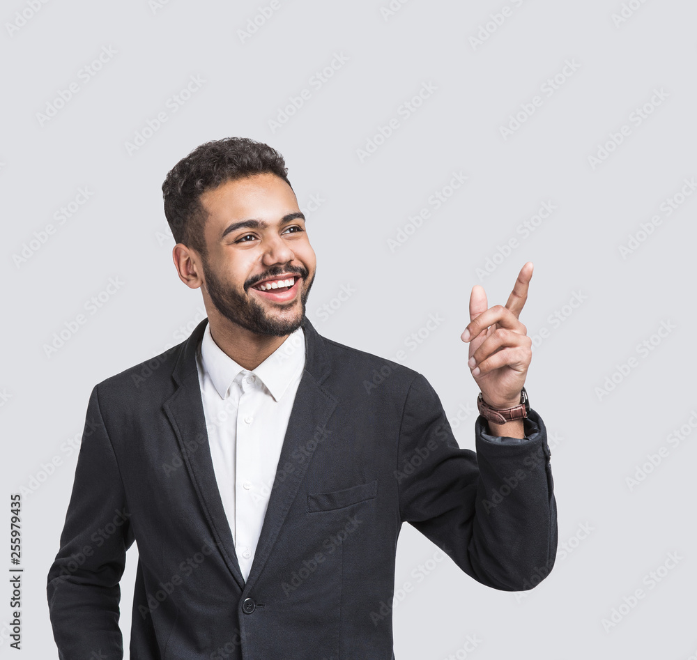 Portrait of handsome smiling young businessman pointing up. Laughing joyful cheerful men isolated studio shot Portrait of handsome smiling young businessman pointing up. Laughing joyful cheerful men isolated studio shot