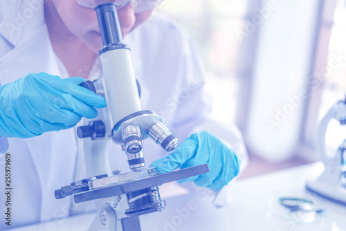 Women scientist looking through microscope in laboratory. Young scientist doing some research with dropper chemical testing.