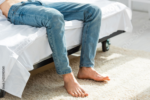 cropped view of man in jeans lying on bed in bedroom © LIGHTFIELD STUDIOS