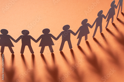 Valokuva Paper people holding hands on red surface