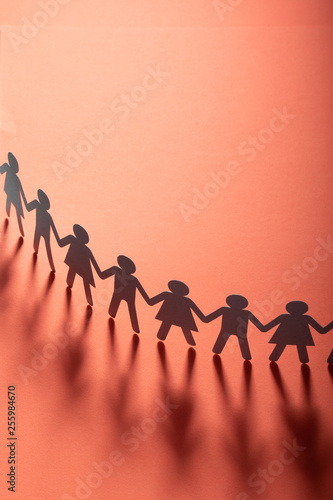 Paper people holding hands on red surface. Community, brotherhood concept. Society and support.