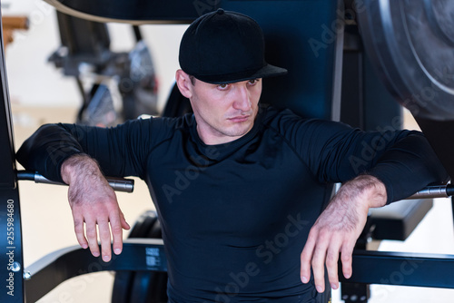 Portrait of male athlete wearing cap sitting at gym photo