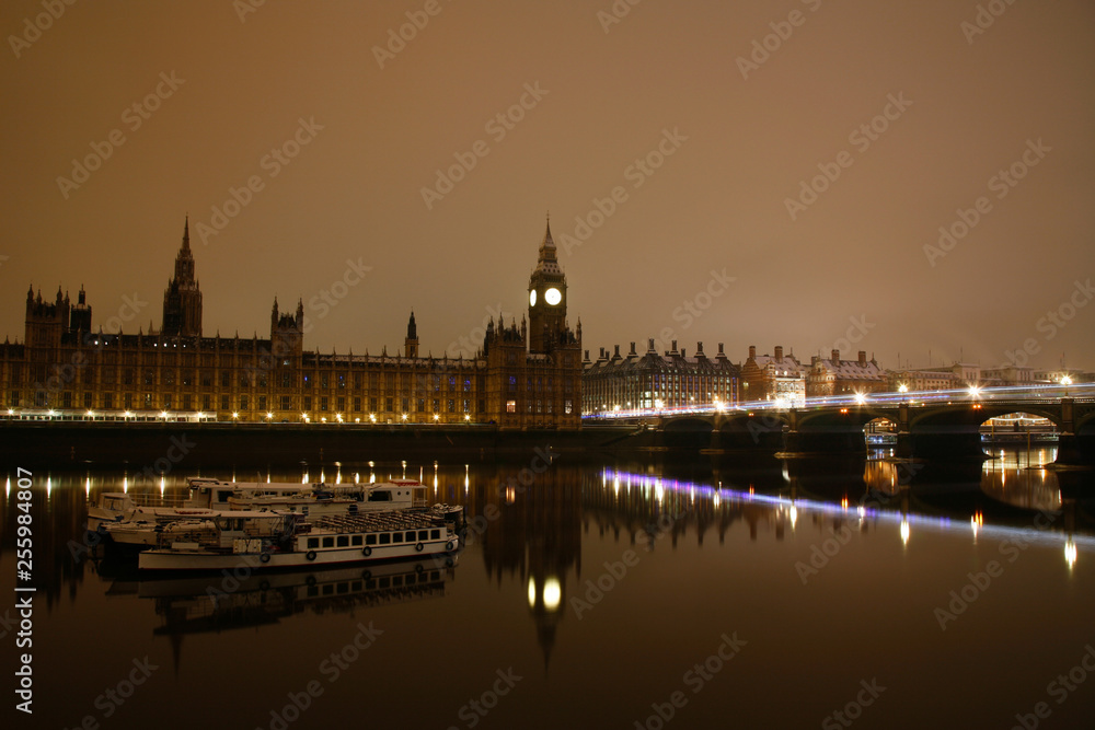 Snow covered Westminster Palace at dawn over dark grey sky