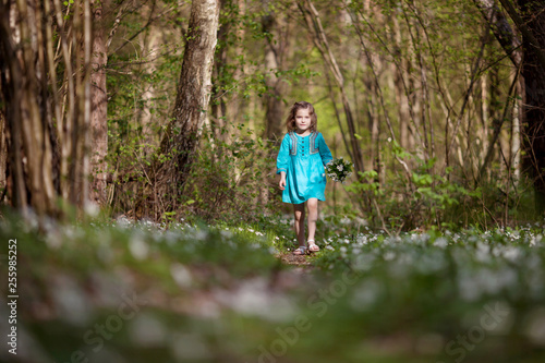 Little girl taking a walk all alone in a park or forest. Cute girl running on the road in the park on a sunny day. Family time.