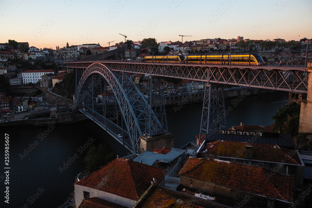 Naklejka premium View of the Luis I Iron bridge with train over the Douro river at dusk, Porto - Portugal.