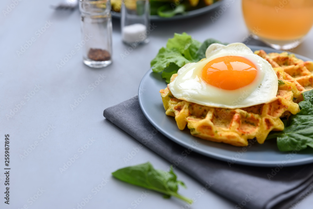Fototapeta premium Spinach cheese waffles with fried egg on gray wooden background. Selective focus.