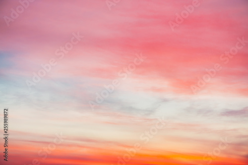 Sunset sky with pink orange light clouds. Colorful smooth blue sky gradient. Natural background of sunrise. Amazing heaven at morning. Slightly cloudy evening atmosphere. Wonderful weather on dawn. © Daniil