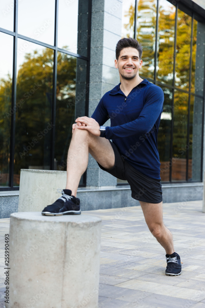 Confident young sportsman doing stretching exercises Confident young sportsman doing stretching exercises