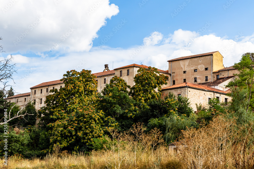 Yellow grass, red tree and old houses near the eresma river at end of Summer, Segovia, Castilla y Leon, Spain