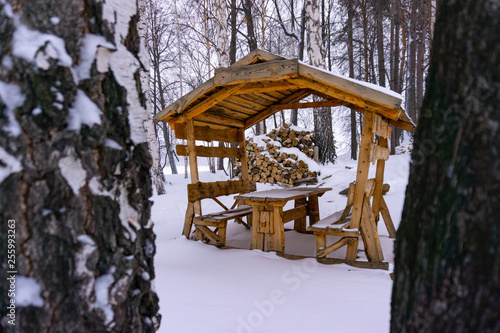 Wooden gazebo in the snow-covered forest