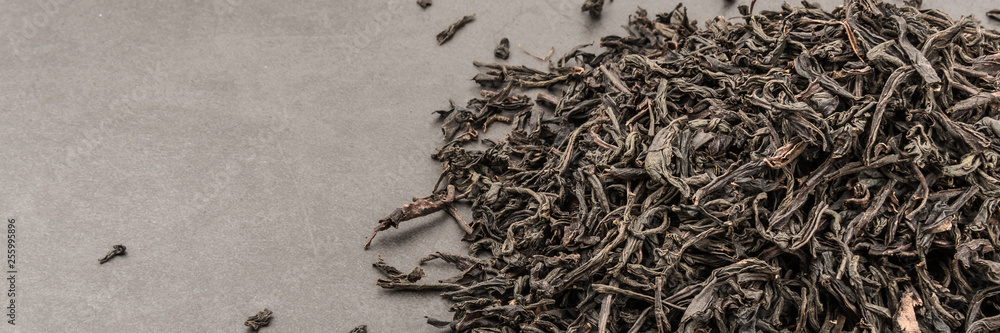 Dried tea is poured scattered on a grey textured background. Dried tea is poured scattered on a grey textured background.