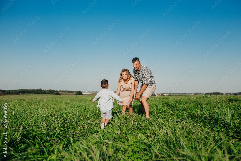 Little boy running to his mother and father in field Little boy running to his mother and father in field