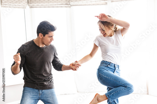 Portrait of joyful couple laughing and dancing while having fun at home