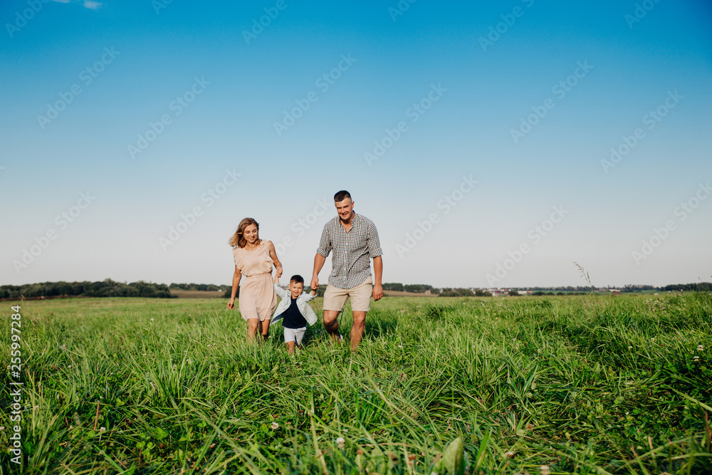 Happy boy with parents running in park. Summertime Happy boy with parents running in park. Summertime