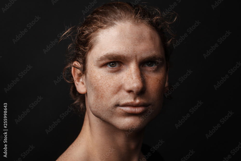 Portrait of a handsome long-haired man with drawn hair and freckles
