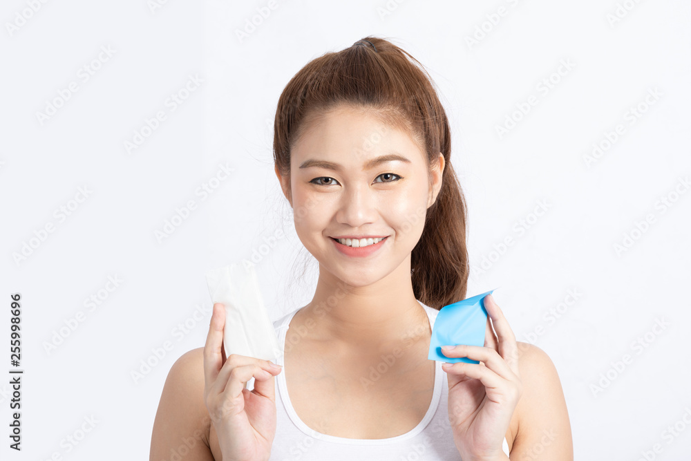 Attractive Asian woman using Facial oil clean film to removal oil and using tissue to removal toner on face for face fresh skin feeling so fresh and clean,Beauty Concept,Isolated on grey background Attractive Asian woman using Facial oil clean film to removal oil and using tissue to removal toner on face for face fresh skin feeling so fresh and clean,Beauty Concept,Isolated on grey background