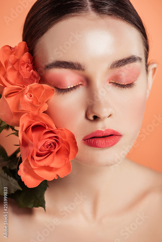 beautiful stylish girl posing with rose flowers isolated on coral