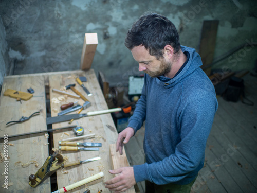 a carpenter with a beard is standing at the carpentry table with tools