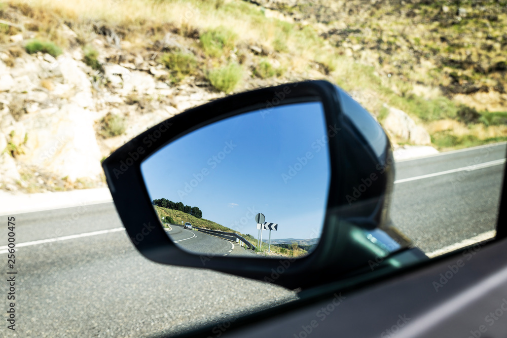 rural highway reflected in the glass of a car mirror