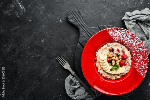 Oatmeal with nuts, banana and wild berries. In the plate. Top view. Flat lay composition Free copy space.