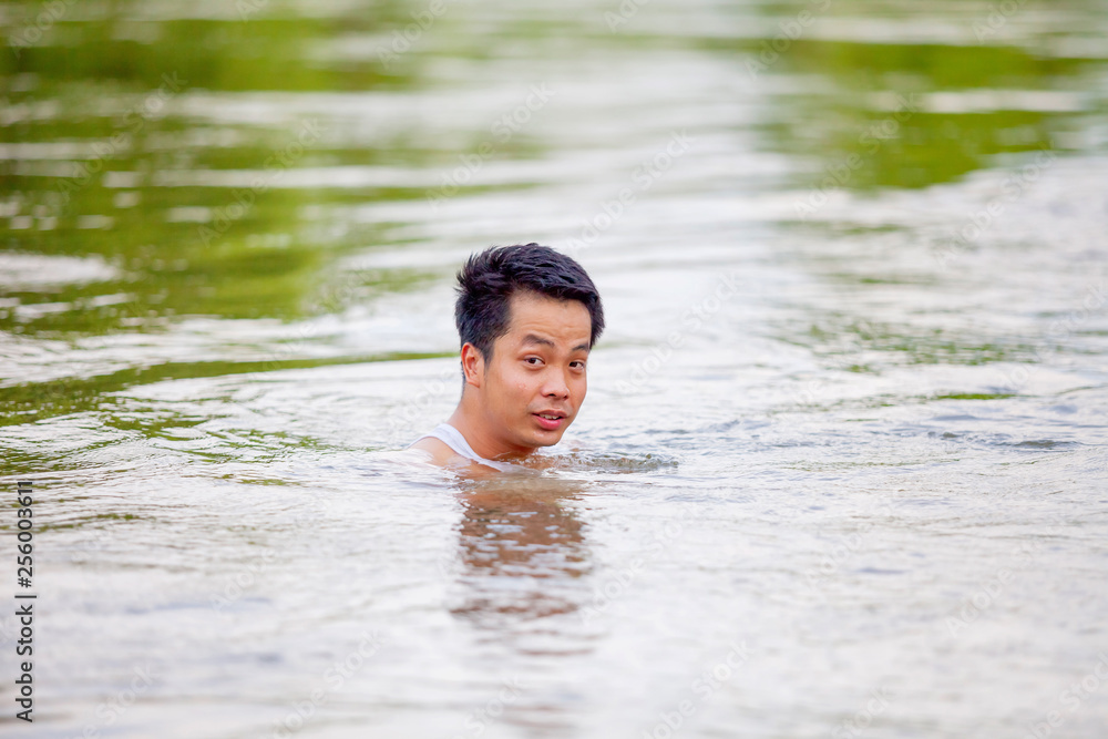 A Thai man in white tank top swimming in river A Thai man in white tank top swimming in river