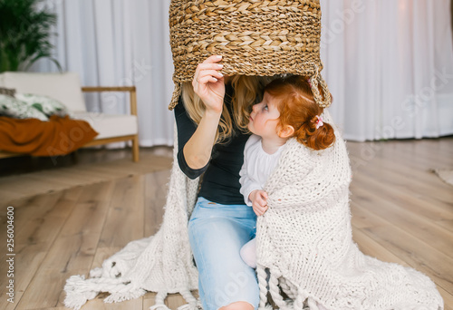 Obraz na płótnie Mother and redhead girl playing home hide and seek, using big basket. w salonie