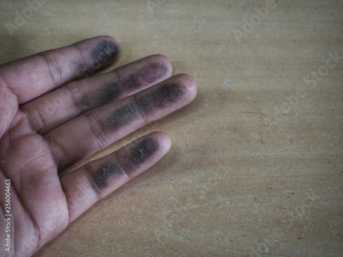 фотографія The fingers of the person who touches the wooden table that is full of black dust makes the fingers dirty