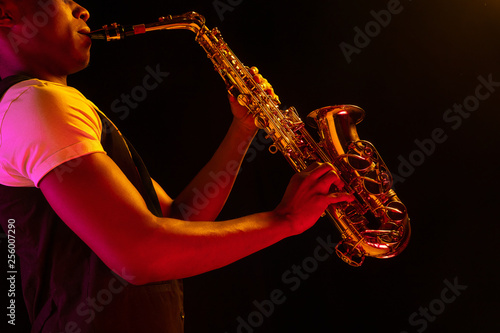 Canvas Print African American handsome jazz musician playing the saxophone in the studio on a neon background