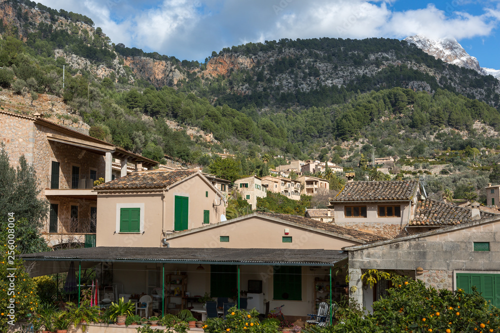 Mediterranes Bergdorf voller alter Häuser umgeben von grünen Bäumen und Bergen. Balearen, Mallorca