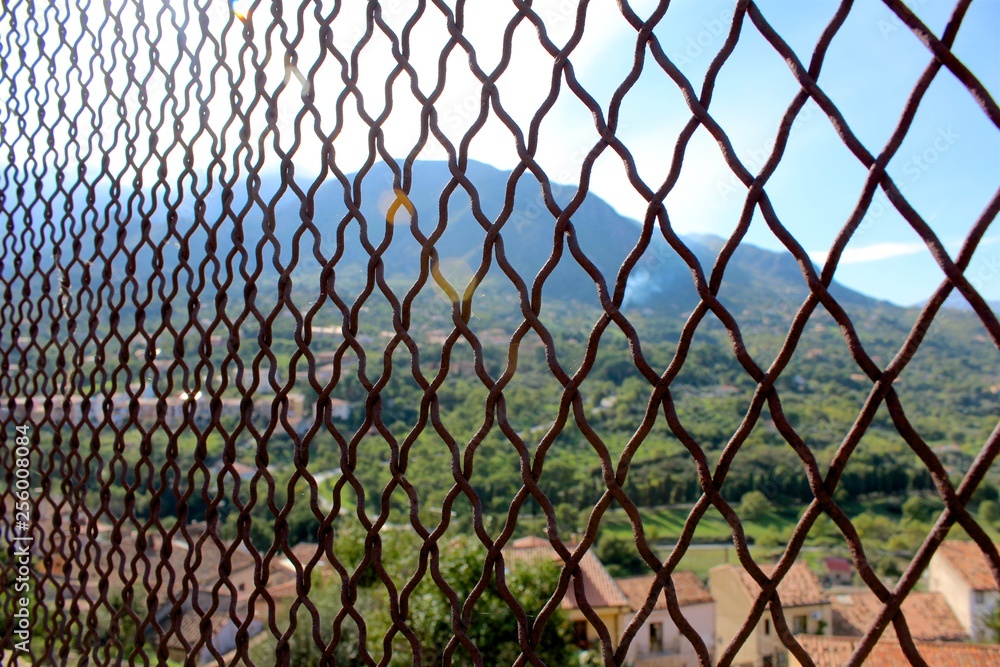 Naklejka premium Sun shining through fence in Cefalu, Sicily
