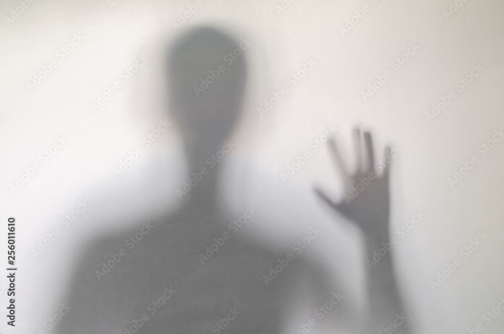 Man waving or rising his hand behind curtain.