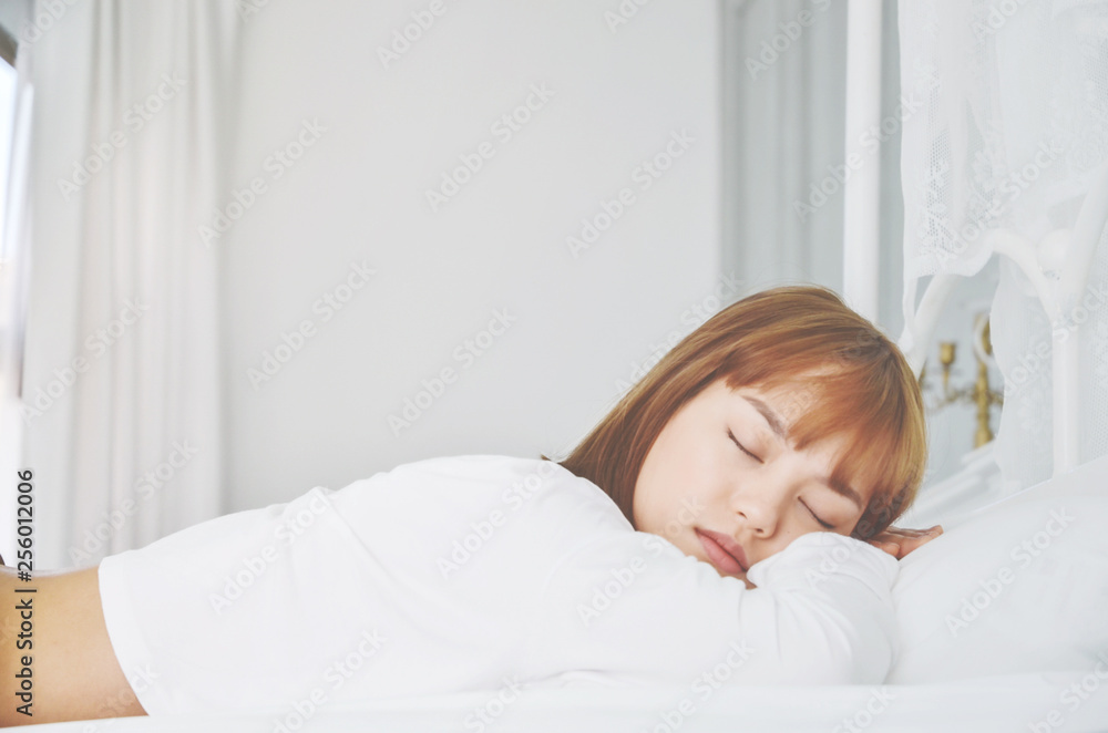 Beautiful woman sleeping in the bedroom..Woman lying face down on the bed.He slept with sleep..A woman wearing a pajama sleep on a bed in a white room in the morning.Do not focus on objects.Warm tone. Beautiful woman sleeping in the bedroom..Woman lying face down on the bed.He slept with sleep..A woman wearing a pajama sleep on a bed in a white room in the morning.Do not focus on objects.Warm tone.