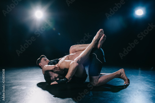 Mma fighter doing chokehold and joint lock to another sportsman during submission wrestling photo