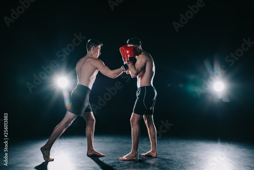 strong sportsmen in boxing gloves fighting during training