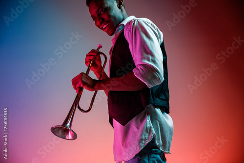 Photography African American handsome jazz musician playing trumpet in the studio on a neon background