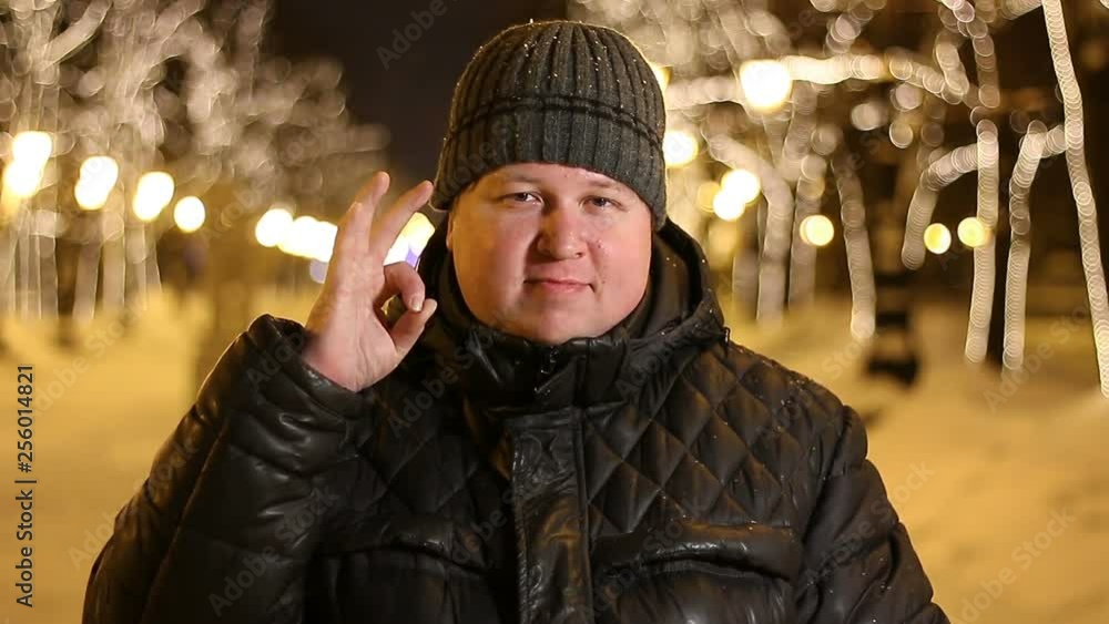 Portrait of fat man showing ok sign outdoors during cold winter evening Portrait of fat man showing ok sign outdoors during cold winter evening