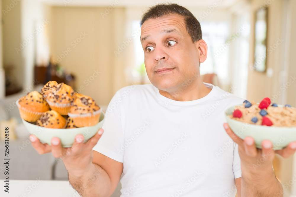 Middle age man trying to choose between healthy food and junk food Middle age man trying to choose between healthy food and junk food